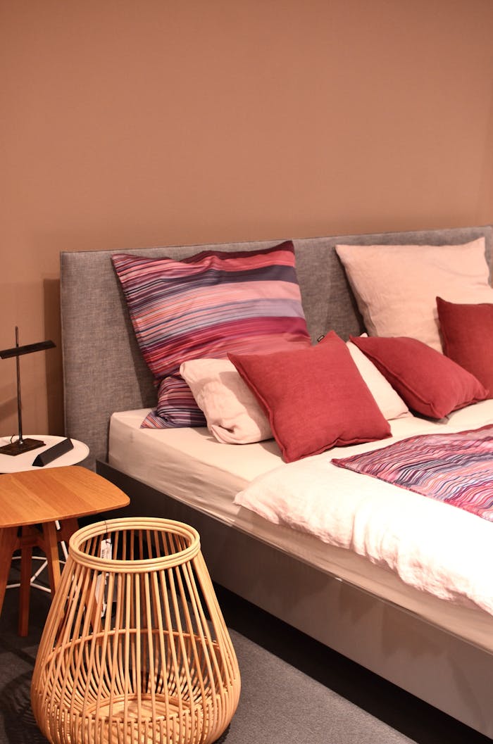 Stylish bedroom scene with colorful pillows, a rattan basket, and modern decor for a cozy interior.
